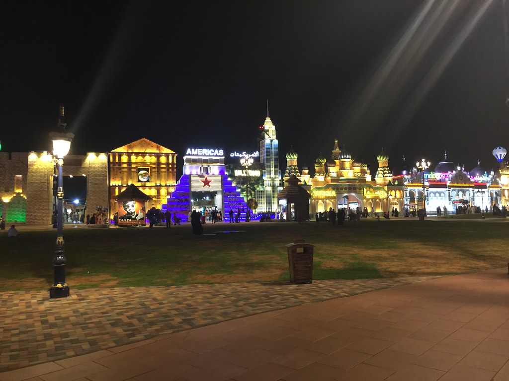 Pabellones iluminados de Global Village Dubái de noche, con el pabellón de las Américas y edificios de inspiración rusa