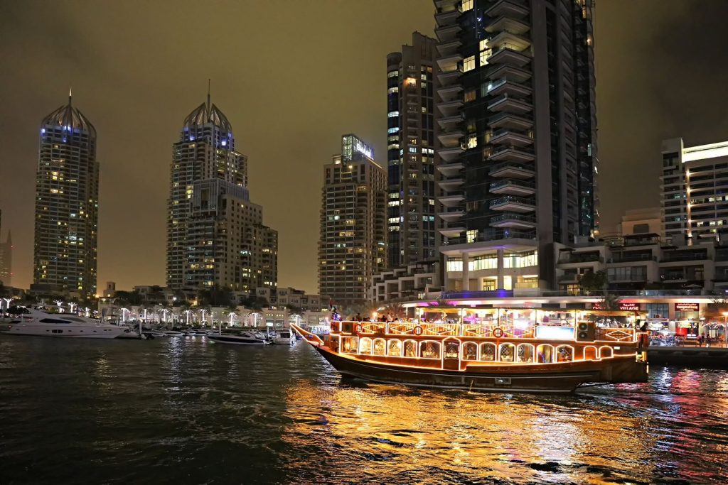 Barco dhow iluminado navegando por Dubai Marina de noche